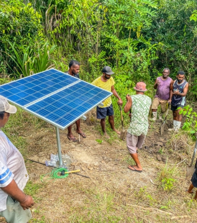 a group of men standing around a solar panel