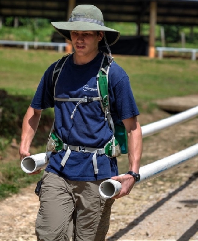 a person wearing a hat and carrying rolled up paper