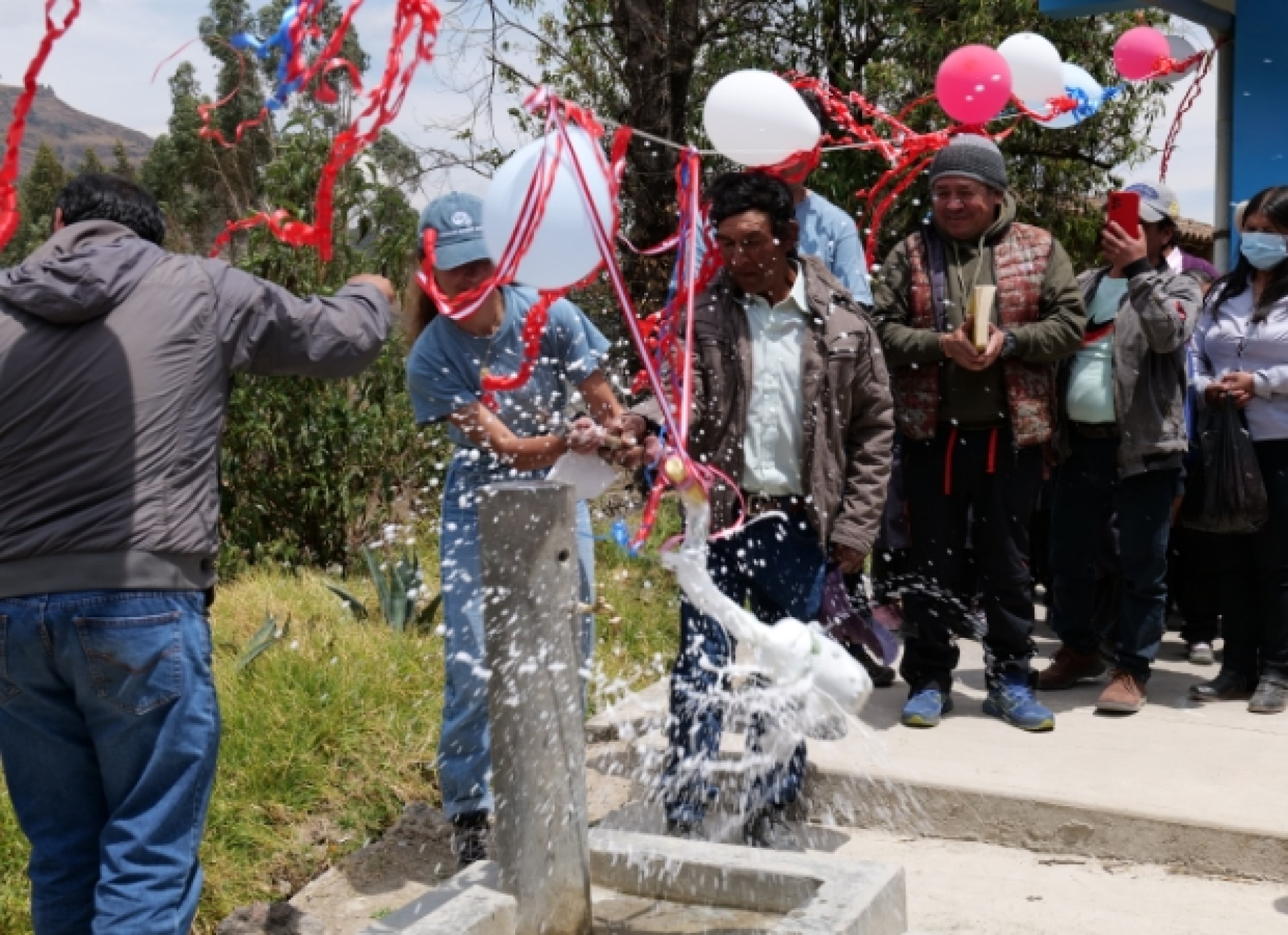 a group of people standing around a fountain with balloons