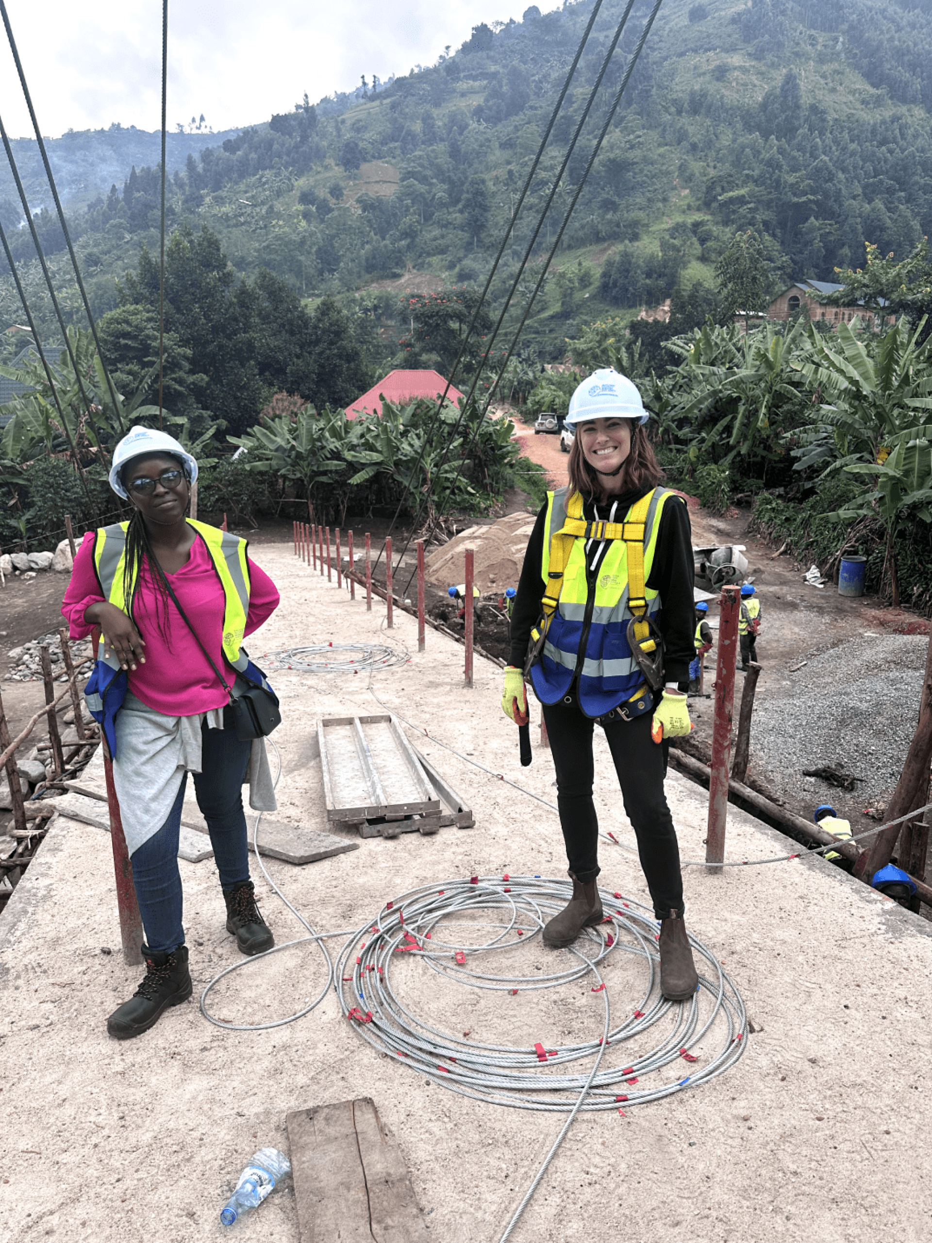 two women wearing safety vests and hard hats standing on a concrete platform