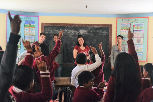 a group of people in a classroom raising their hands