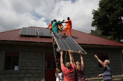 a group of people on a roof with solar panels