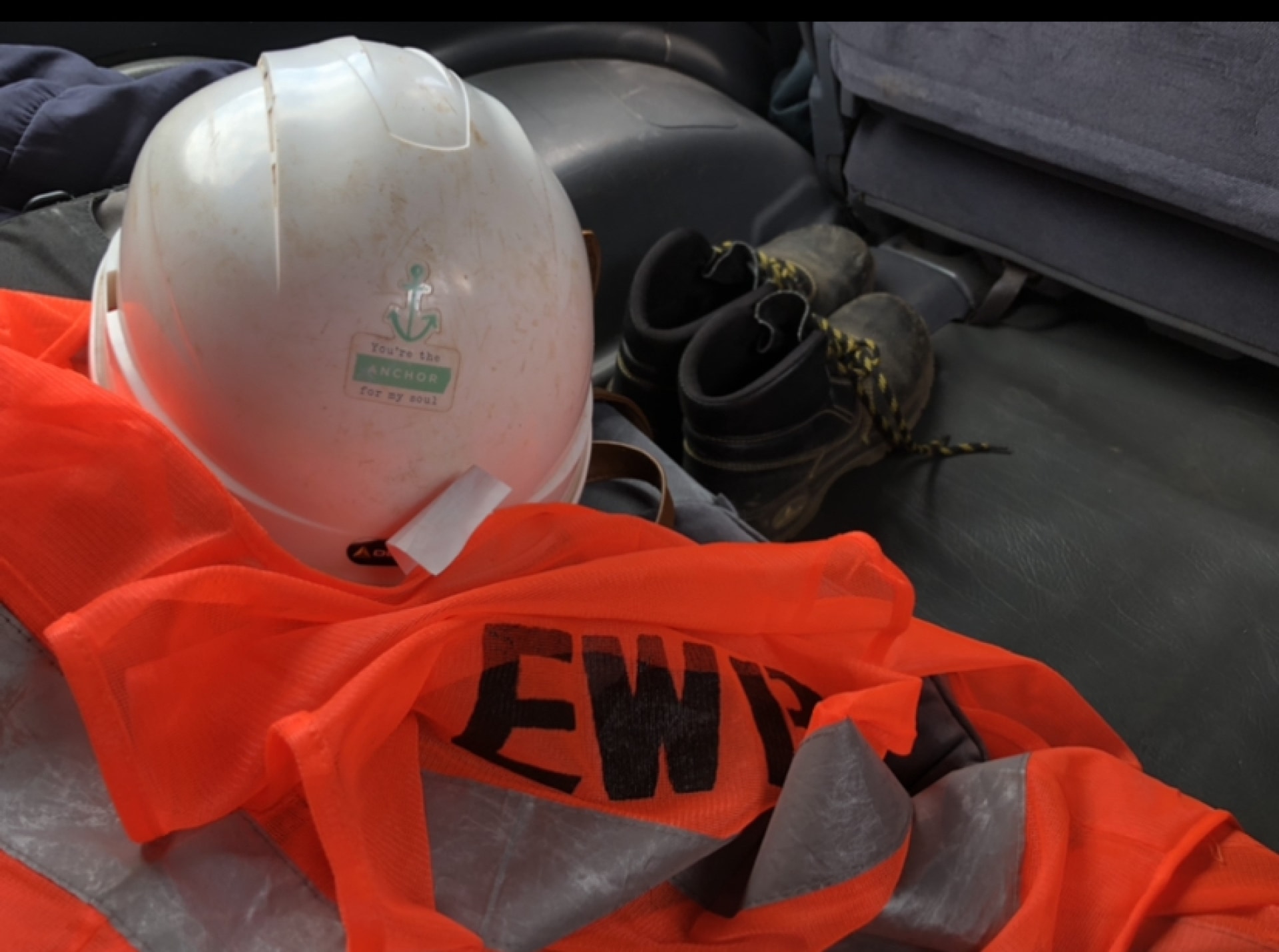 In the back of a vehicle, a white hard had sit atop a high-visibility vest and next to a pair of steel-toed boots