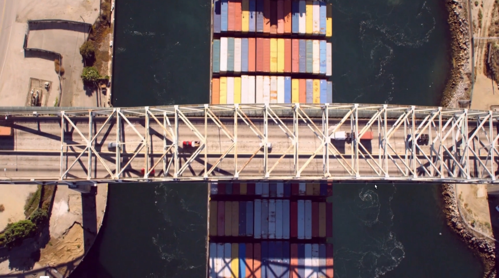 aerial view of a bridge with a freight ship passing under it