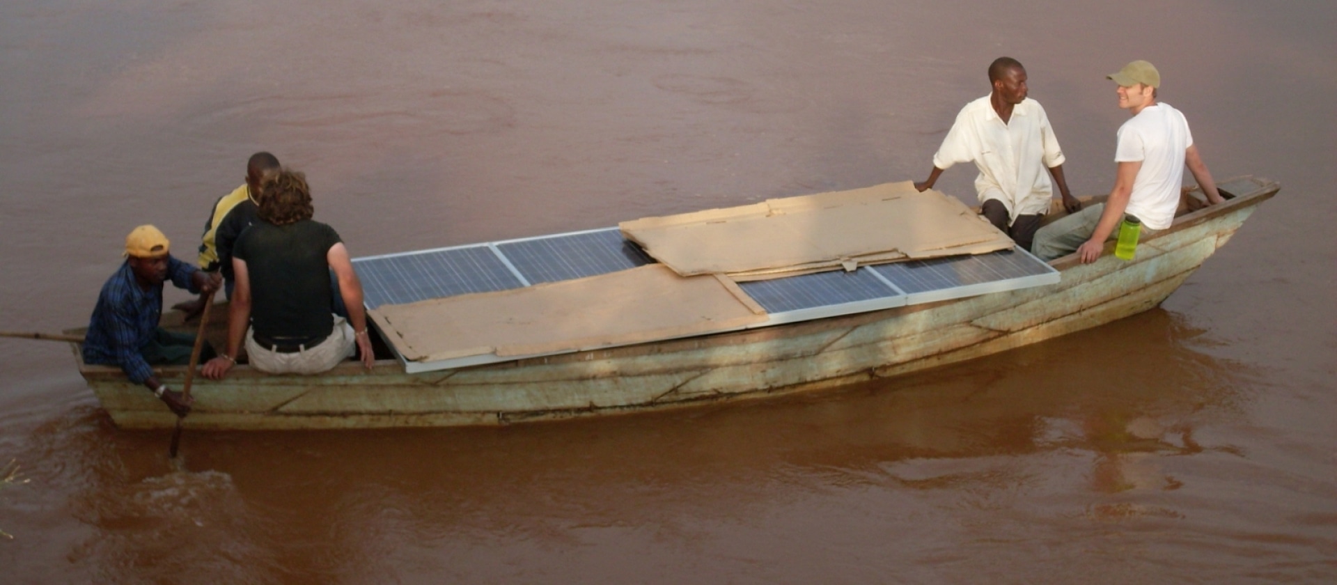people in a boat moving solar panels across a river